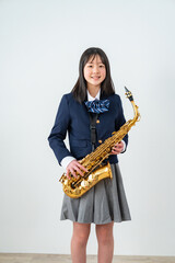 Fototapeta premium アルトサックスを持って笑顔の制服姿の日本人少女