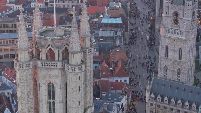 Drone close-up of the Belfry of Ghent with Christmas decorations, capturing tourists enjoying the festive streets of the historic city center.