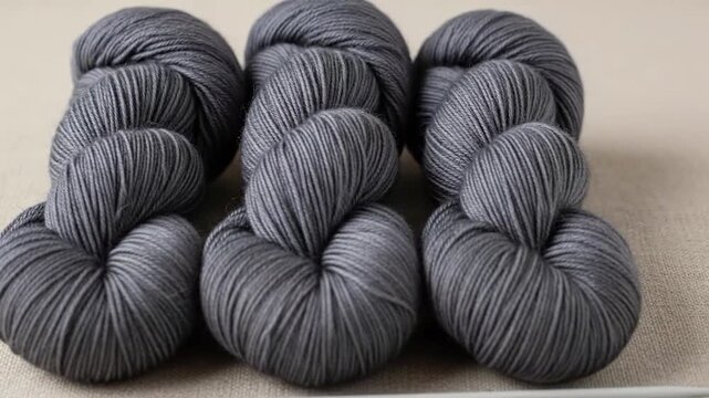 Series of gray skeins of yarn arranged in multiple groups on neutral background