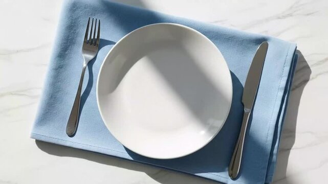 Empty White Plate with Silver Cutlery on Blue Napkin Over Marble Surface in a Repeating Pattern