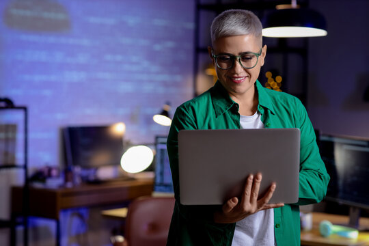 Female programmer working with laptop in office at night
