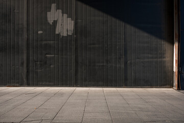 Black wooden wall and pavement shadow forming an urban street scene © zhu difeng