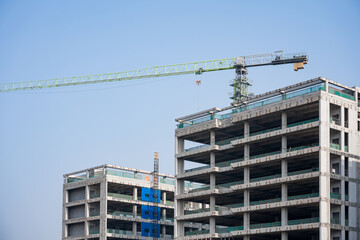 Under construction high-rise building with tower crane against clear blue sky © zhu difeng