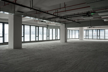 Obraz premium Empty unfinished office space in a modern commercial building with exposed concrete structure and large windows