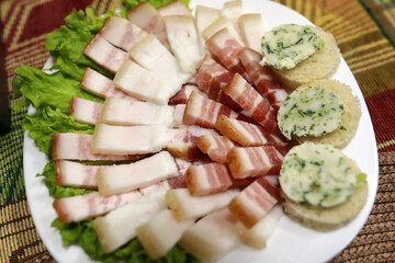 Sliced fat and bacon on white plate