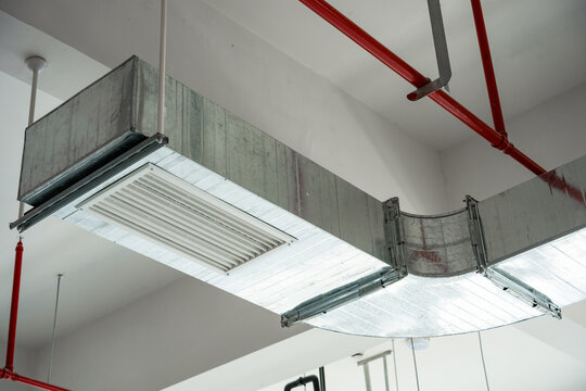 Indoor ceiling-mounted metal ventilation ducts with fire protection piping systems