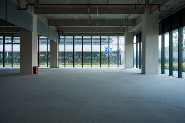 Spacious unfinished industrial-style office interior with concrete floor and exposed structural elements