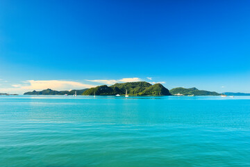 Fototapeta premium A beautiful view of Langkawi island against a beautiful blue sky with some boats in the distance on the horizon. Tropical scenery. located at Kedah, Malaysia - September 25 2024: