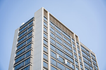 Fototapeta premium Modern high-rise office building captured from a low angle against a clear blue sky