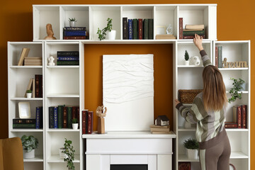 Young woman taking book from bookshelf in stylish home library