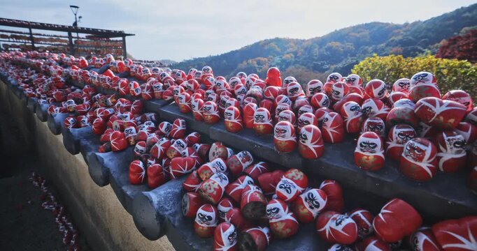 Countless tiny daruma dolls scattered across roof top - steady cam movement forward