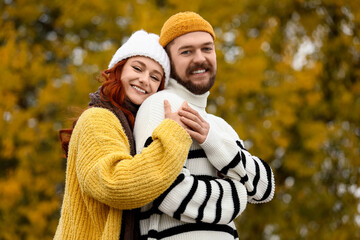 Fototapeta premium Cute young couple in warm sweaters hugging at autumn park