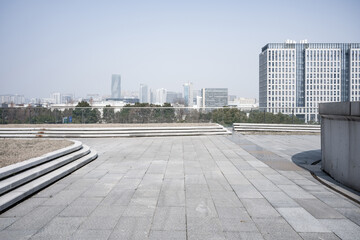 Empty urban plaza with stone pavement and modern high-rise buildings in the distance © zhu difeng