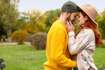 Fototapeta premium Cute young couple in warm sweaters bonding at autumn park