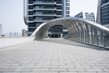 Modern arched pedestrian bridge connecting high-rise buildings in an urban business district © zhu difeng