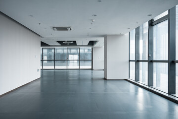 Modern office space with empty corridor and large floor-to-ceiling windows allowing natural light