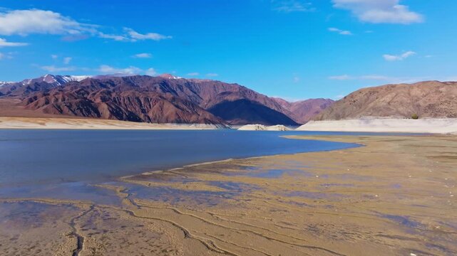 Aerial view captures vast Orto Tokoy reservoir surrounded by arid mountains under. Daytime scene conveys tranquility and natural beauty of Kyrgyzstan.