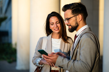 Business colleagues using smartphone outdoors, discussing work