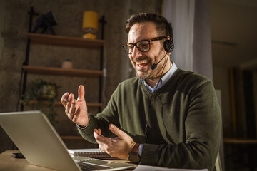 Happy man having video call wearing headset at home