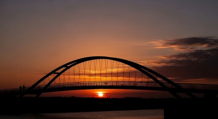 Obraz premium Sunset over a modern arch bridge.