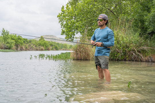 Male Angler Fly Fishing While Wading in River