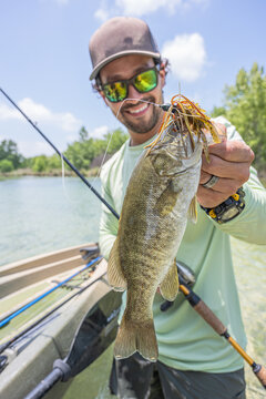Hispanic Male Angler Displaying Largemouth Bass with Fishing Lure