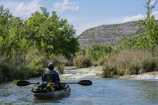 Angler Kayaking on Scenic River with Mountain Landscape Background