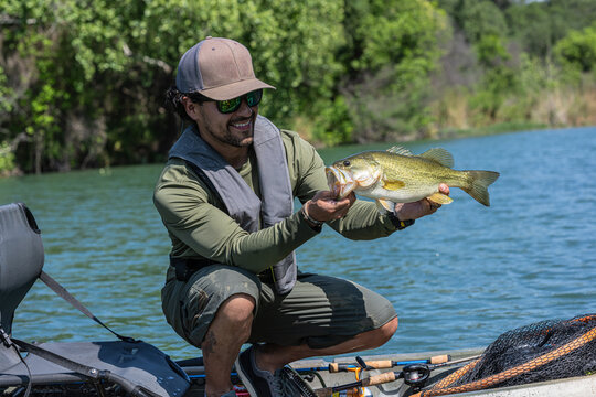Hispanic Male Angler Holding Largemouth Bass on Kayak in Lake