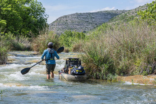 Male Angler Pulling Loaded Kayak Through Rocky Rapids