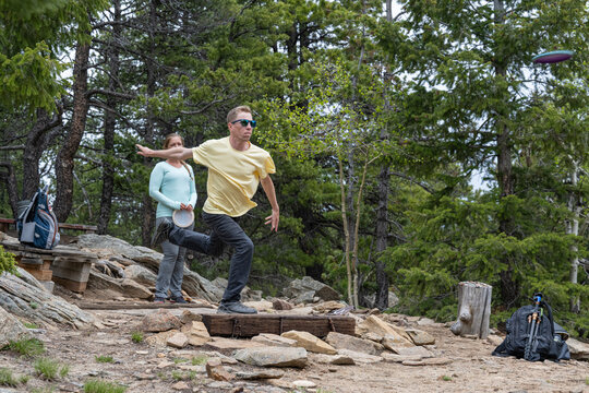 Caucasian Man Throwing Disc Golf Frisbee on Rocky Mountain Course