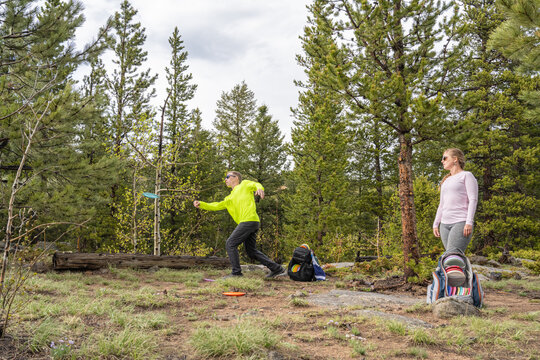 Couple Playing Disc Golf in a Scenic Evergreen Forest During Summer