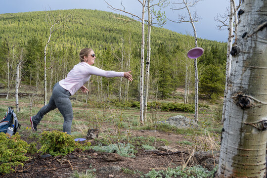 Woman Throwing a Precision Disc Golf Putt Among Aspen Trees