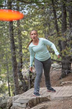 Young Woman Playing Disc Golf in a Mountain Forest Course
