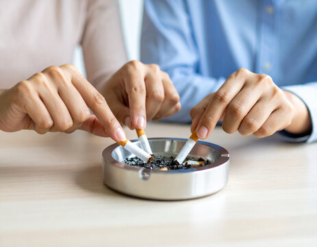 A closeup of a businessman&rsquo;s hand holding a lit cigar while working at an office desk