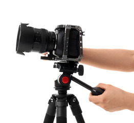 Photographer setting up modern photo camera on tripod against white background