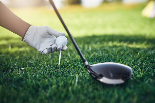 Hands, golf ball and tee off at country club for games, contest and gloves with sports equipment on grass. Person, golfer and peg in ground for shot, gear or target for play at course in summer