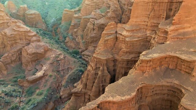 Aerial view captures majestic eroded red sandstone canyon rock layers in Kyrgyzstan. High angle view.