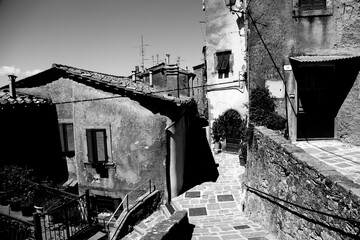 Obraz premium Borghi toscani in bianco e nero. L'architettura medievale dei borghi toscani, caratterizzata da pietra, cotto, riflette il periodo comunale con cinte murarie, torri, vicoli stretti e piazze. Italia. 