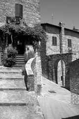 Obraz premium Borghi toscani in bianco e nero. L'architettura medievale dei borghi toscani, caratterizzata da pietra, cotto, riflette il periodo comunale con cinte murarie, torri, vicoli stretti e piazze. Italia. 