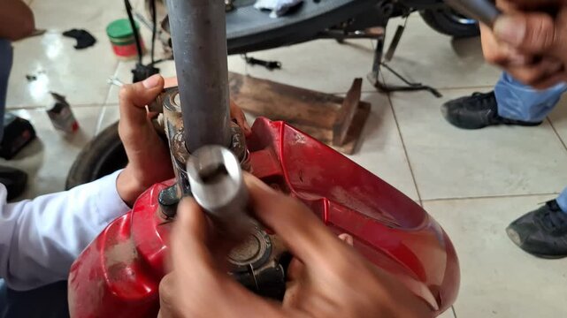 Vocational student practicing motorcycle shock absorber removal during mechanical training workshop