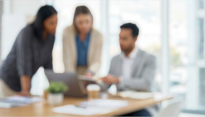 Three blurred individuals collaborate on a project in an office setting. One person points at a document while the other two observe and discuss. Natural light fills the space.