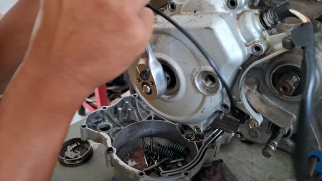 Vocational students performing hands-on motorcycle maintenance training by installing and assembling a clutch pack inside an engine crankcase in a technical workshop