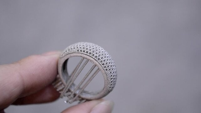 Object printed on 3D printer from metal powder by laser sintering. Woman holding metal ring in hand created on metal 3D printer. Selective laser melting technology. New modern 3D printing technologies