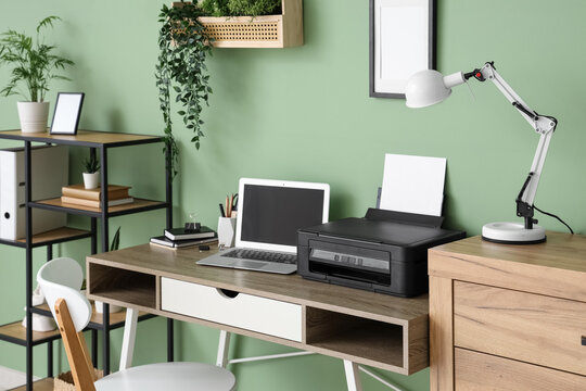 Workplace with modern printer, laptop and desk lamp in stylish home office