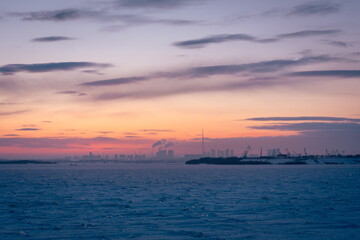 Obraz premium Soft pastel sunset illuminating the frozen landscape and silhouetted urban skyline of Heihe city
