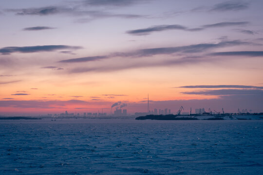 Soft pastel sunset illuminating the frozen landscape and silhouetted urban skyline of Heihe city
