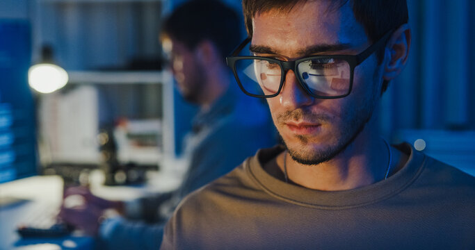 Closeup team adult male freelance work late typing write prompt AI bot app program nomad terminal code at office night. Artificial intelligence dashboard, robotics, user interface, machine learning.