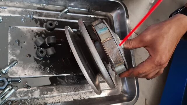 Close-up of a vocational student cleaning CVT automatic scooter transmission components with aerosol spray cleaner in a workshop