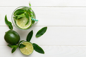 Obraz premium Caipirinha, Mojito cocktail, vodka or soda drink with lime, mint and straw on table background. Refreshing beverage with mint and lime in glass top view flat lay