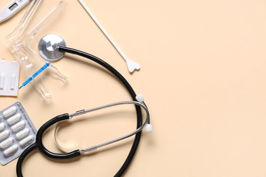 Set of gynecological supplies and stethoscope on beige background